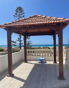 a wooden gazebo on a patio with the ocean at Alshrooq Village 97 in Borg El Arab