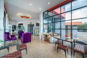 a lobby with purple chairs and tables and windows at Belleville hotel in Phetchabun