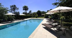 a swimming pool with chairs and umbrellas at La Résidence du Moulin in Tourrettes-sur-Loup