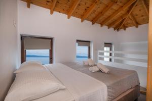 a white bedroom with a large bed with two pillows at Grande Blu by NG Villas in Afitos