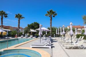 a swimming pool with lounge chairs and umbrellas at Akritas Hotel Pefkochori in Pefkochori
