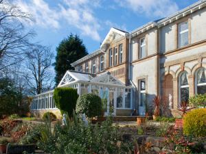 a large house with a greenhouse in front of it at Rosslea Hall Hotel in Rhu