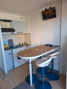 a kitchen with a wooden table and two stools at Appartement vu mer in Le Barcarès