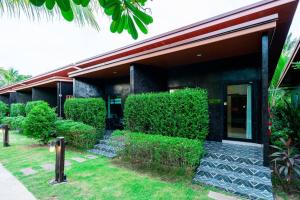 a black building with green bushes next to a building at S Garden View Resort in Ban Bang Yai Chuai +4 photos