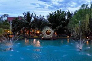 a pool with fountain in a resort at night at S Garden View Resort in Ban Bang Yai Chuai