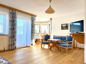 a living room with a table and chairs and a television at Ferienwohnungen Billovits in Kössen