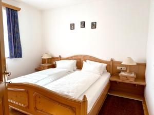 a bedroom with a wooden bed with white sheets and pillows at Ferienwohnungen Billovits in Kössen