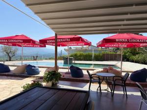 a patio with red umbrellas and chairs and a pool at Vila Marjana in Sarandë