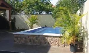 a swimming pool with a stone wall and two palm trees at El rincón de Sánchez in Moca