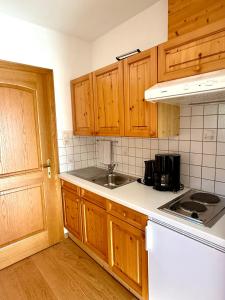 a kitchen with wooden cabinets and a sink at Ferienwohnungen Billovits in Kössen