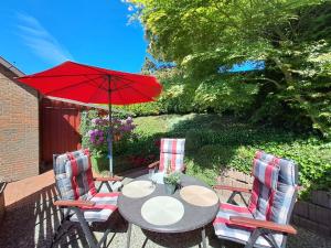a table with two chairs and a red umbrella at Ferienwohnung Rahn in Freienwill