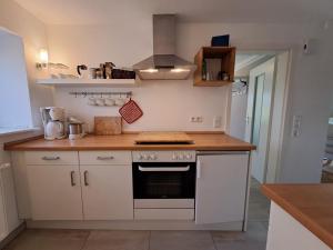 a kitchen with white cabinets and a stove top oven at Ferienwohnung Rahn in Freienwill