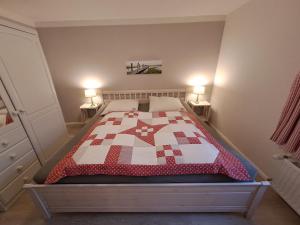 a bedroom with a bed with a red and white quilt at Ferienwohnung Rahn in Freienwill