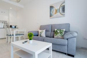 a living room with a blue couch and a white table at Lux Sevilla Apartment Piscina in Bormujos