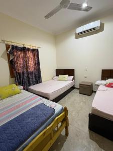 a room with three beds and a ceiling fan at Villa Layan الريف الاوروبي in Madīnat as Sādāt