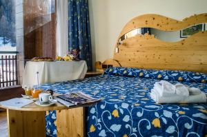 1 dormitorio con 1 cama con cabecero de madera y mesa en Hotel Rivè - Complesso Turistico Campo Smith, en Bardonecchia
