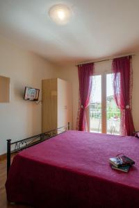 a bedroom with a bed with a red bedspread at B&B Alle Tre Rose in Montignoso