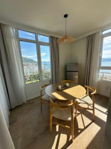 a dining room with a table and chairs and windows at Lungomare ViewPoint in Vlorë