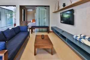 a living room with a blue couch and a coffee table at Condominio Frente Mar 3 suites com Ar Cond piscina e Hidro privativa in Mata de Sao Joao +51 photos