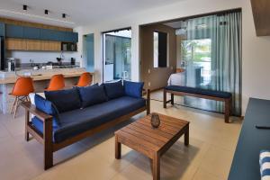 a living room with a blue couch and a kitchen at Condominio Frente Mar 3 suites com Ar Cond piscina e Hidro privativa in Mata de Sao Joao