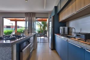 a kitchen with blue cabinets and a counter top at Condominio Frente Mar 3 suites com Ar Cond piscina e Hidro privativa in Mata de Sao Joao