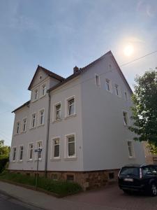a white building with a car parked in front of it at Stay&Work Döbeln - Hermsdorfer Straße in Döbeln