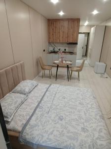a bedroom with a bed and a table and a kitchen at ЖК Akjol in Astana