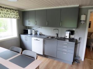 a kitchen with gray cabinets and a table with chairs at Higravstinden Basecamp - Lofoten in Laupstad +7 photos