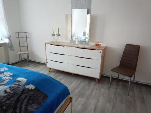 a bedroom with a dresser with a mirror and a chair at Ferienwohnung Alte Post in Knorrendorf