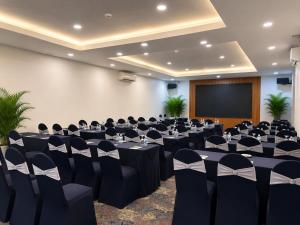 a conference room with black tables and chairs and a screen at Oscar Saigon Hotel in Ho Chi Minh City