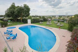 a swimming pool with blue chairs and tables and a yard at Casa Do Vale Hotel by Umbral in Évora