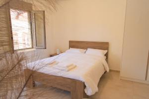 a bedroom with a bed with white sheets and a window at Central cozy studio in Agios Nikolaos