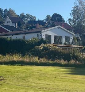a white house with a field in front of it at Nye leiligheter nær Strand og rideklubb på Fevik! in Grimstad