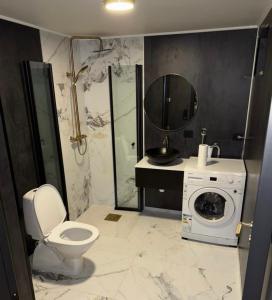 a bathroom with a toilet and a washing machine at Nye leiligheter nær Strand og rideklubb på Fevik! in Grimstad