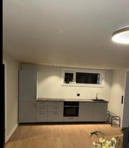 a large kitchen with white cabinets and a flat screen tv at Nye leiligheter nær Strand og rideklubb på Fevik! in Grimstad +4 photos