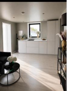 a kitchen with white cabinets and a table in a room at Nye leiligheter nær Strand og rideklubb på Fevik! in Grimstad