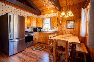a kitchen with a table and a stainless steel refrigerator at Spacious Rustic Cabin with Vaulted Ceilings, Full Kitchen, Fireplace & Large Deck Near Babbitt, Minnesota in Babbitt