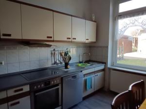 a kitchen with white cabinets and a sink and a window at Ferienwohnung Alte Post in Knorrendorf