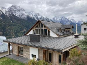 Ein Haus mit Dach, im Hintergrund Berge in der Unterkunft Chasa Sentima in Sent
