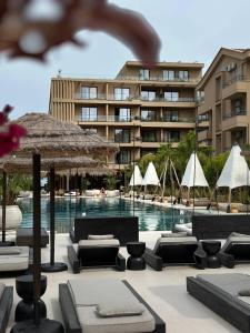 a pool with chairs and umbrellas in front of a building at Palmera Escape Radhime in Vlorë