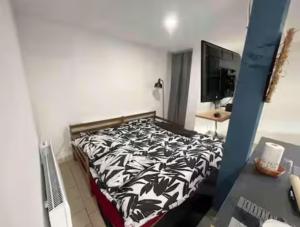 a bedroom with a bed with a black and white comforter at Studio avec terrasse in Château-lʼÉvêque