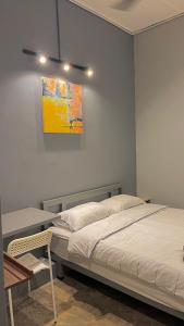 a bedroom with a bed and a desk and a painting at Roomah En-suite attached-bath R6 in Ipoh