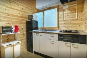a kitchen with a black refrigerator and a stove at イーリス軽井沢 in Naganohara