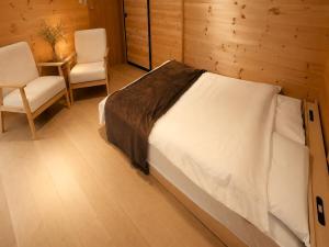 a bedroom with a large bed and two chairs at イーリス軽井沢 in Naganohara