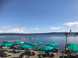 a beach with green umbrellas and boats in the water at Casa Belvedere in Mazzano Romano