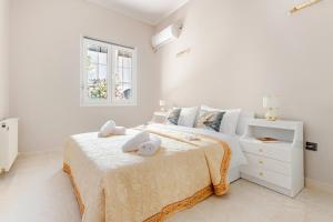 a white bedroom with a bed with two stuffed animals on it at Enora Loutraki Guesthouse in Loutraki