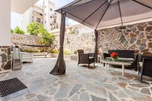 a patio with an umbrella and chairs and a table at Enora Loutraki Guesthouse in Loutraki