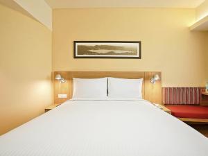 a bedroom with a large white bed and a red couch at ibis Bengaluru Hosur Road - An Accor Brand in Bangalore