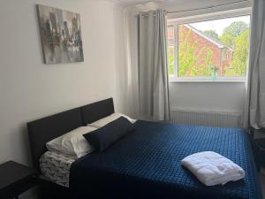 a bedroom with a bed with a blue comforter and a window at A Home from Home -2 Bed Flat & Free Driveway Parking in Ascot