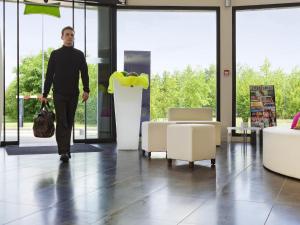a man walking through a room with chairs and tables at ibis Styles Compiegne in Jaux